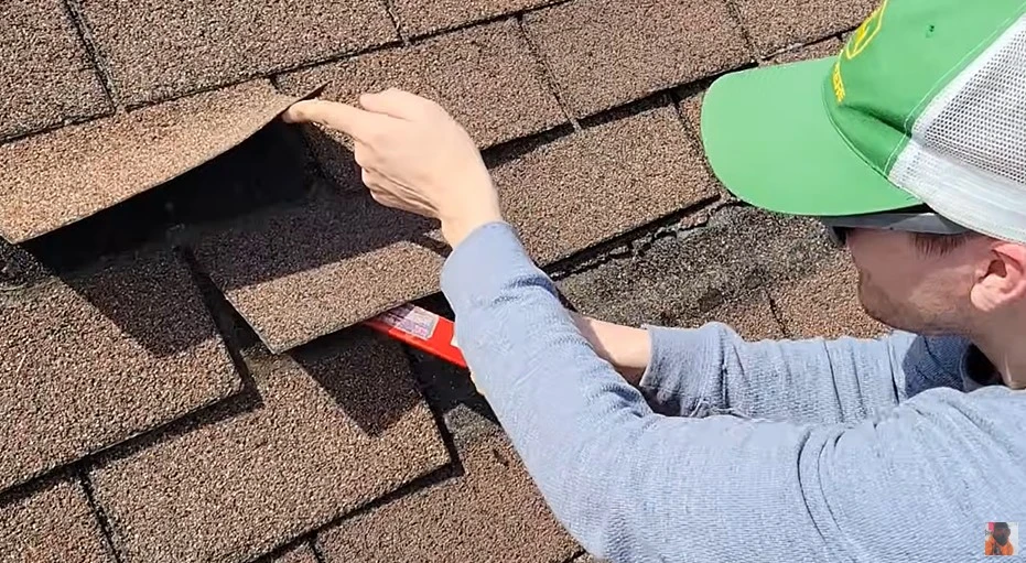 Worker assessing damaged shingles for repair vs replacement
